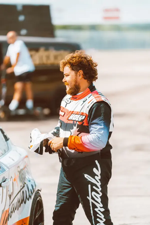 Photographie d’Etienne Moustache lors de l’événement La Boiserie, portant une tenue de pilote de course.